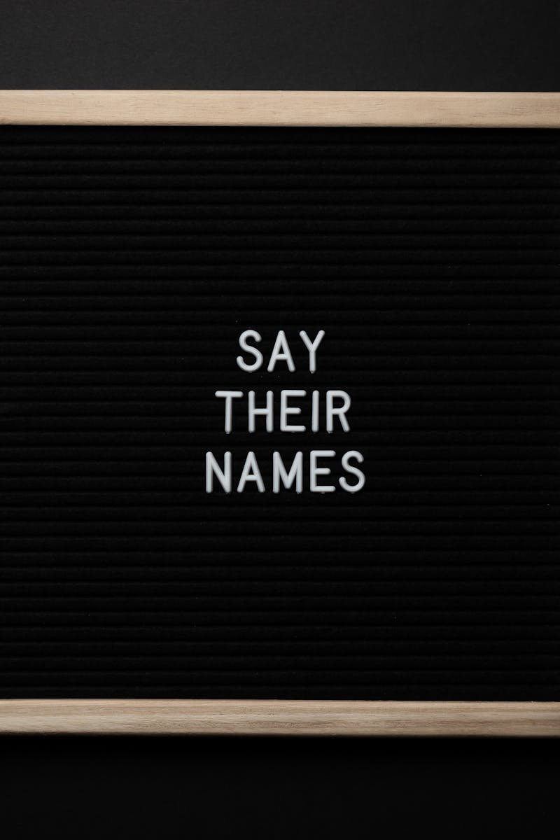 Top view composition of black framed photo with white text Say Their Names placed on black background