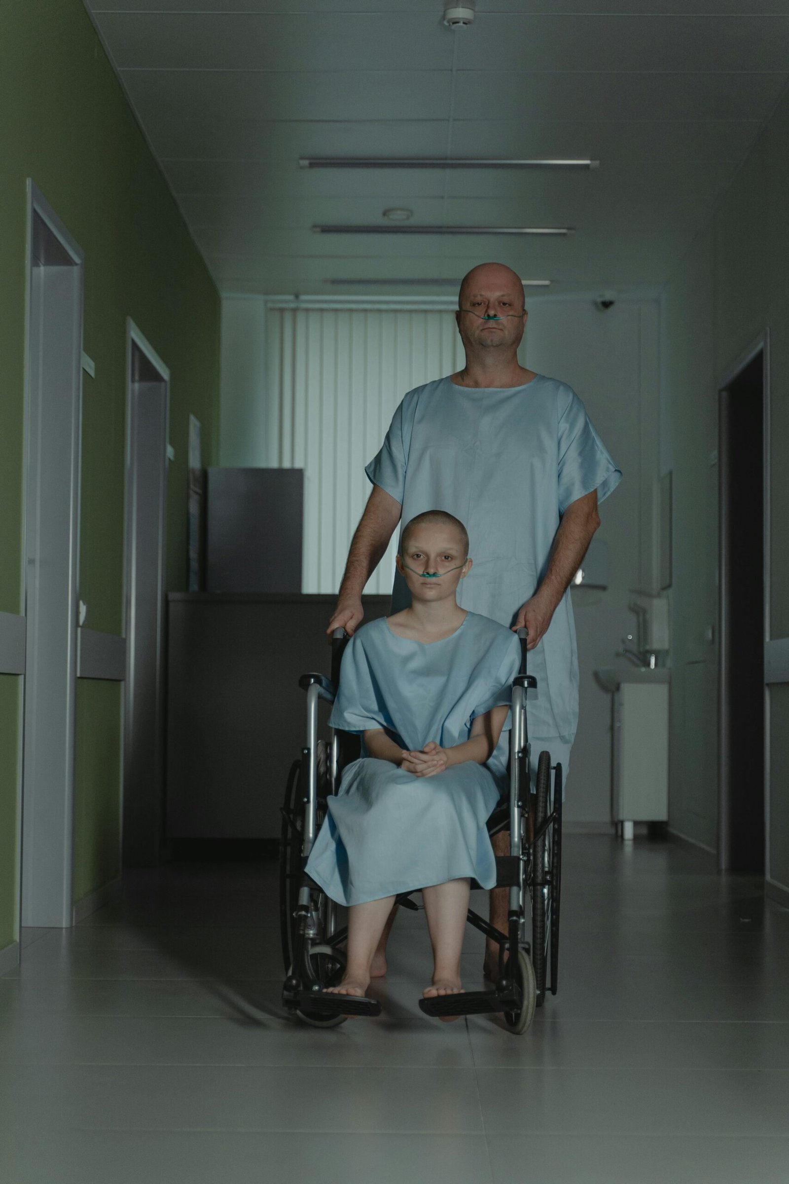 A somber hospital scene showcasing two patients, one in a wheelchair, highlighting themes of struggle and illness.